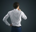 Thinking concept with pensive businessman in white shirt and glasses standing on abstract black wall background Royalty Free Stock Photo