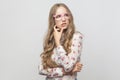 Thinking concept. Puzzlement long haired blonde woman in pink eyeglasses, touching her chin and looking up. Royalty Free Stock Photo