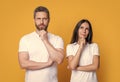 Thinking couple stroking chins studio. Couple thinking isolated on yellow. Thoughtful couple