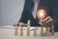 Thinking and creative, Businessman hand holding light bulb on the wooden people, Teamwork and idea concept, Successful team leader Royalty Free Stock Photo