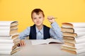 Thinking cute boy pupil in prosess of studying with a lot of books.