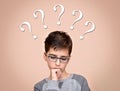 Thoughtful young boy with question marks above his head