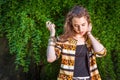 Portrait of Young Woman standing outdoors by green leaves, looking down, thinking Royalty Free Stock Photo