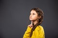 Thinking grimacing serious schoolgirl looking up on grey studio background. Back to school. The concept of education