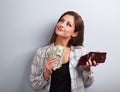 Thinking happy woman holding dollars and wallet in hands and wan