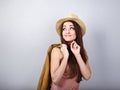 Thinking happy woman in pink t-shirt and suumer straw hat holding leather jacket and looking up on blue background. Closeup