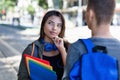 Thinking latin american female student talking with male student in city Royalty Free Stock Photo