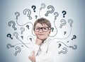 Thinking little boy, question marks on gray wall Royalty Free Stock Photo