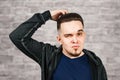 Thinking man holds hand at face, on brick wall background Closeup portrait of young pensive guy. Caucasian male model Royalty Free Stock Photo