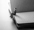 Thinking man, miniature man sitting alone on notebook.