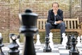 Thinking man sitting at a life sized outdoor chess board Royalty Free Stock Photo