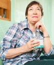 Thinking mature woman with pills and glass of water Royalty Free Stock Photo