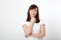 Thinking middle aged woman in white polo T-shirt isolated on white, copy space.