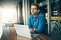 Thinking of my next move. a handsome young businessman sitting alone and looking contemplative while using his laptop in Royalty Free Stock Photo