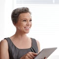 Thinking about online opportunities. A mature businesswoman looking thoughtful while holding her digital tablet. Royalty Free Stock Photo