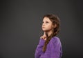 Thinking sad dreamy serious cute kid girl looking up on grey studio background with empty copy space. Closeup Royalty Free Stock Photo