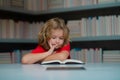 Thinking school kid. Schoolboy reading book in library. Kids development, learn to read. Pupil reading books in a school Royalty Free Stock Photo