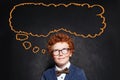 Thinking schoolboy and big empty speech cloud bubble on chalkboard background Royalty Free Stock Photo