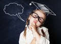 Thinking schoolgirl wearing graduation hat in classroom Royalty Free Stock Photo