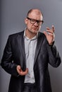 Thinking serious bald business man in eyeglasses and suit discussing and have an idea on grey background. Closeup