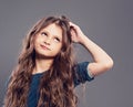 Thinking serious cute kid girl scratching the head and looking up on grey studio dark background with empty copy space. Closeup Royalty Free Stock Photo