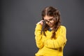 Thinking serious kid girl with folded arms in eyeglasses looking on grey studio background. Back to school. The concept of Royalty Free Stock Photo