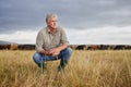 Thinking, serious and professional farmer on a field with herd of cows and calves in a open nature grass field outside