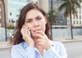 Thinking woman in a blue blouse at phone in the city Royalty Free Stock Photo