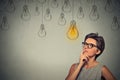 Thinking woman in glasses looking up with light idea bulb above head Royalty Free Stock Photo