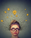 Thinking woman in glasses with question signs and light idea bulb above head looking up wondering Royalty Free Stock Photo