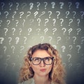 Thinking woman looking up at many questions marks above head Royalty Free Stock Photo