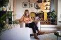Thinking woman using earphones and cellphone and sitting in an armchair at home Royalty Free Stock Photo