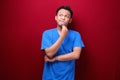 Thinking Young asian man is seriously think gesture on red background Royalty Free Stock Photo