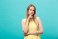 Thinking young confident woman in yellow dress looking up isolated on blue background Royalty Free Stock Photo