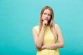 Thinking young confident woman in yellow dress looking up isolated on blue background Royalty Free Stock Photo