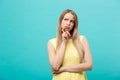 Thinking young confident woman in yellow dress looking up isolated on blue background Royalty Free Stock Photo