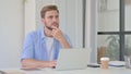 Thinking Young Man Working on Laptop in Office Royalty Free Stock Photo