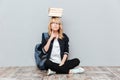 Thinking young woman student holding books on head. Royalty Free Stock Photo