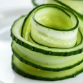 Thinly sliced cucumber layers are artfully arranged into a rose-like shape. The