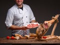 Smiling happy chef is holding a plate with thinly sliced jamon Royalty Free Stock Photo