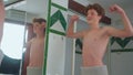 A thinness teenager looks at his body in the mirror. The guy notices changes in his appearance, the teenager turns into