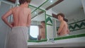 A thinness teenager looks at his body in the mirror. The guy notices changes in his appearance, the teenager turns into