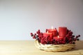 Third advent with four red candles, three of them are lighted, arranged in a light willow wicker wreath with artificial berries, Royalty Free Stock Photo