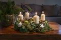 Third Advent, wreath with three burning white candles and Christmas decoration on a wooden table in front of the couch, festive Royalty Free Stock Photo