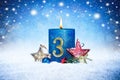 Third sunday of advent blue candle with golden metal number red decoration one on wooden planks in snow front of silver panorama Royalty Free Stock Photo