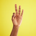 Third times a charm. Studio shot of an unrecognisable man showing three fingers against a yellow background. Royalty Free Stock Photo