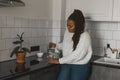 Thirsty african american woman drinking mineral water in kitchen, pouring healthy liquid from jug to glass, happy lady