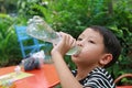 Thirsty Asian little boy drink water from plastic bottle in the garden Royalty Free Stock Photo