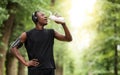 Thirsty black sportsman drinking water, jogging at park