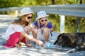 Thirsty black stray dog drinking water from the plastic bottle on hot summer day. Two kids giving cool water to thirsty dog Royalty Free Stock Photo